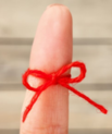 red string tied around index finger with a bow