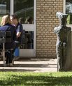 Studerende sidder ved borde i et grønt område ved Aarhus Universitets gule mure