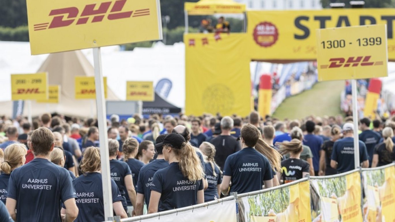 Many runners from Aarhus University stand ready to run among a large group of other runners at the DHL Relay Race.