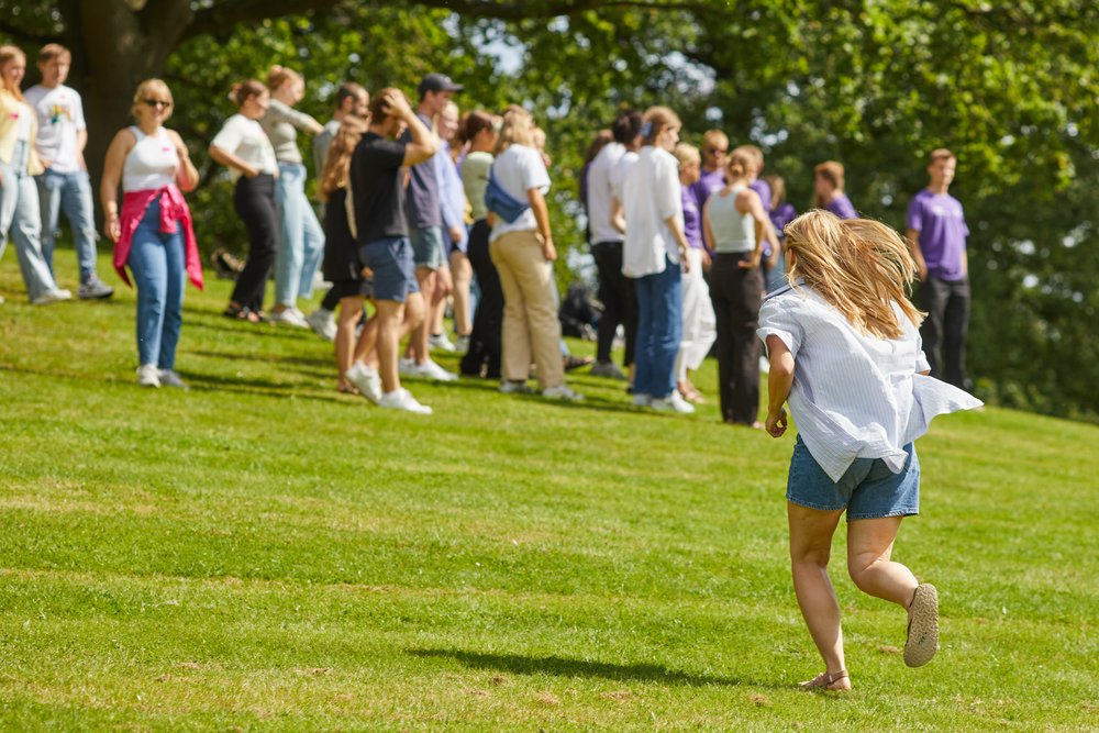 Girl running up the lawn during introduction week at Aarhus University