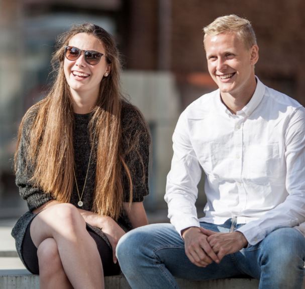 To smilende universitetsstuderende udenfor i solskin